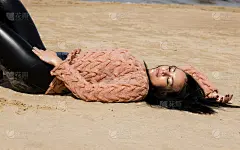 这位美丽的黑发女子穿着针织套衫在波罗的海海岸摆姿势
