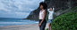 Two people stand on a beach looking at the water