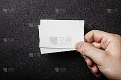 男人的手上拿着两张白色的名片