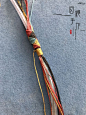 This may contain: a close up of a piece of string with writing on the bottom and an orange, yellow, red, and blue cord attached to it