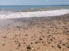 海卵石，蓝色的海，波浪，灿烂的太阳。景观壁纸和自然概念。温暖的夏日大海，天气好时浪小。
