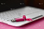 明亮的粉红色 usb 闪存卡与粉红色的弓躺在毯子柔软和毛茸茸的粉红色羊毛织物旁边的白色笔记本电脑。记