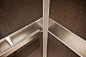 Rectangular Handrail in Satin Stainless Steel, shown in LEVELe-105 Elevator Interior with upper and lower panels in Bonded Bronze with Dark Patina and Charleston pattern; handrail panels in Stainless Steel with Seastone finish