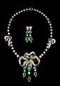 这组首饰套件来自1880年代的欧洲，项链及耳坠成套，以祖母绿为主石，金银叠打满嵌耀目钻石，织成柔美浪漫的蝴蝶结，可单独作为胸针佩戴