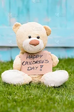 泰迪熊拿着纸板，上面写着儿童节快乐