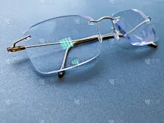 黄金钛眼镜与无框框架与清晰的光学镜片与防眩光在黑暗的框架。