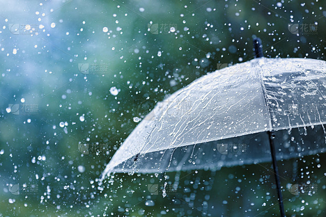 透明的伞在雨点的映衬下溅起水滴。雨天的概...