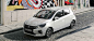 A white 2024 Mitsubishi Mirage Compact Hatchback parked on a stone street in front of a mural wall