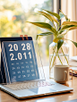vmjecm_an_empty_glass_calendar_on_a_desk_next_to_plant_and_lapt_7d0c0cdd-8a4d-4dac-9da0-5b210e959ae8