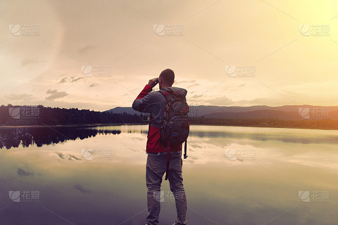 一个背着背包的年轻人站在湖边