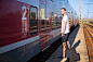 Caucasian man with a suitcase next to the train wearing casual summer clothes.