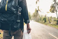 后视图的人与背包徒步旅行和行走在森林的道路上。背包旅行的概念。