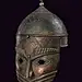 Helmet with hemispherical, iron skull, decorated with engraved cartouches featuring inscriptions in Arabic surrounded by woven racemes, at the top a lily-shaped cusp with round knot and conical base; at the mask, fixed with rivets, relieved decorations an