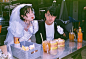 This may contain: two people sitting at a table with drinks and condiments in front of them