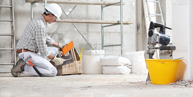 泥水匠和建筑工人在有脚手架的室内建筑工地...