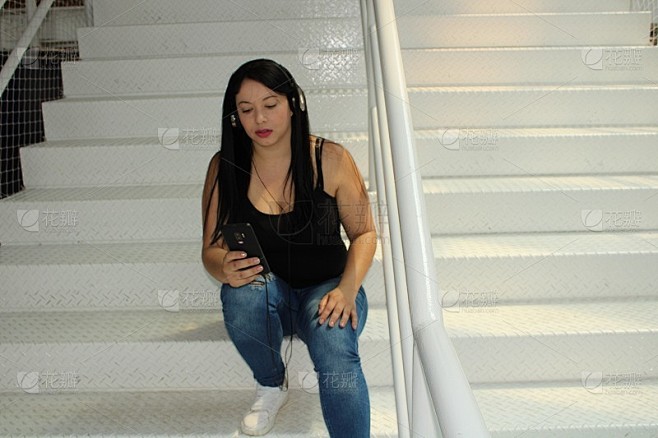 女人用手机和耳机听音乐