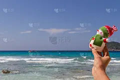 圣诞快乐的雪人戴着圣诞老人的帽子在阳光明媚的海滩上，新年假期概念休闲旅游在炎热的南方国家
