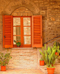 Love the neutrality of the tan brick with the punchy orange shutters and flowers.: 