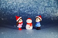 孩子们在亮闪闪的纸背景上雕刻雪人。新年贺卡上有一个女孩和一个穿冬装的男孩