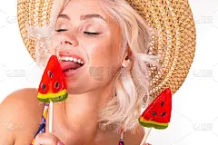 漂亮的金发白人女性站在西瓜棒棒糖泳衣和微笑孤立在白色的背景