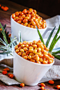 Fresh sea buckthorn in white porcelain bowls on vintage wooden b