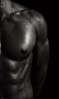 赤裸上身的肌肉男站在黑色背景下照片素材