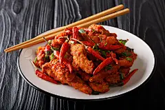 Traditional spicy szechuan chicken in Schezwan sauce close-up on a plate. horizontalTraditional spicy szechuan chicken in Schezwan sauce close-up on a plate on the table. horizontal