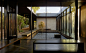 Looking through glass panels into a central area with benches that surround a 'pool' of stones with a single plant in.