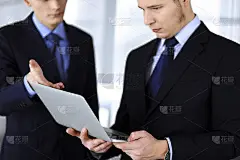 商务人士在会议上讨论演示，站在一个现代化的办公室里。一个不知名的商人和一个同事在电脑上搜索一些信息，
