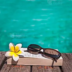 Book and sunglasses, blue water background