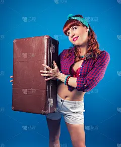 漂亮的海报女郎摆姿势与复古手提箱对抗蓝色