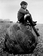 Boy sitting on a sea mine, Kent, England, 1945.

