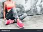 Fitness sport woman in fashion sportswear doing yoga fitness exercise in the city street over gray concrete background. Outdoor sports clothing and shoes, urban style. Sneakers closeup.