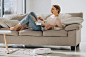 young-woman-lying-sofa-reading-book-while-robot-vacuum-cleaner-doing-housework_1303-27198