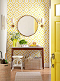 entry vignette: yellow wallpaper, narrow console table, plants, round mirror
