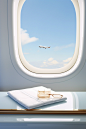 an airplane window with a mirror in front and a jewelry box on the table, in the style of light sky-blue and light white, large-scale minimalist, neutral color palettes, clean-lined, light white and light gold