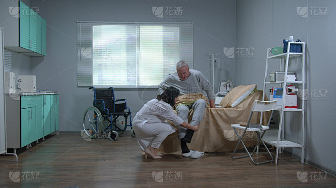 穿白色制服的医生帮助老病人从床上起来