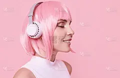 亮粉色头发的时髦女孩戴着耳机听音乐