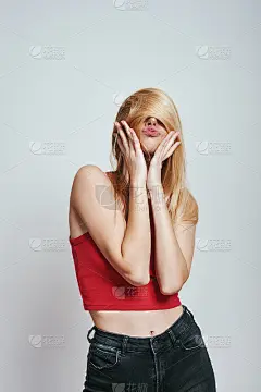 要疯了。年轻女子在红色背心覆盖脸与她的头发和做滑稽的脸，而站在灰色的背景