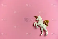粉红色背景上有金色角和尾巴的独角兽