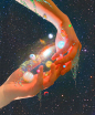 two hands reaching out towards each other in front of the stars and planets above them