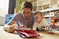 Mid adult man and baby daughter reading storybook in playroom_创意图片