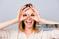 Happy laughing woman making binoculars using her hands against gray background Eye Stock Photo