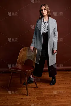 漂亮的年轻女性，穿着经典的套装，黑色的鞋子和灰色的外套。古董椅子。女人的衣服。