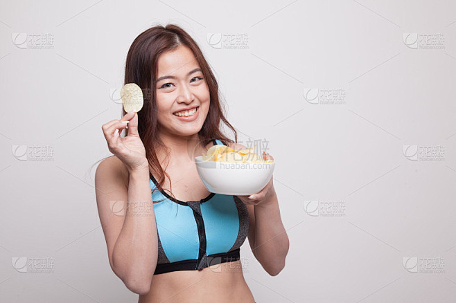 美丽的亚洲健康女孩吃薯片。