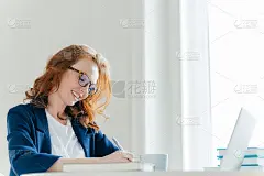 室内用姜头发喜洋洋的女子拍照，签合同，坐在柜子前的笔记本电脑。微笑的董事为财务报告记录信息，在笔记本