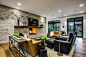 Example of a transitional medium tone wood floor and brown floor living room design in Dallas with white walls, a two-sided fireplace, a stone fireplace and a wall-mounted tv