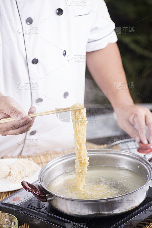 厨师用筷子夹着锅里的面条