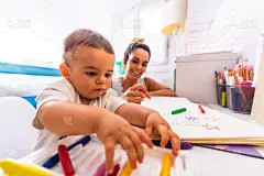 年轻的白人母亲在房间里和她玩玩具。宝宝不到一年就学会了妈妈的第一课。用彩色颜料作画