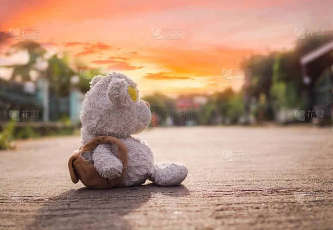 破碎的心的概念。独自的泰迪熊坐在夕阳下的路上。传达一种寂寞、懊恼、失恋的心情。